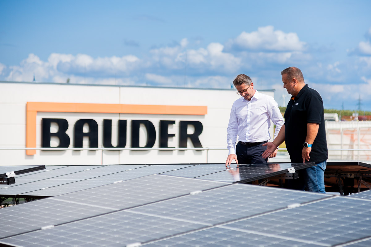 Zwei Personen diskutieren über die Vorteile der Nutzung von Photovoltaikanlagen auf Gebäudedächern. Unternehmensfotografie für den Dachspezialisten Bauder.