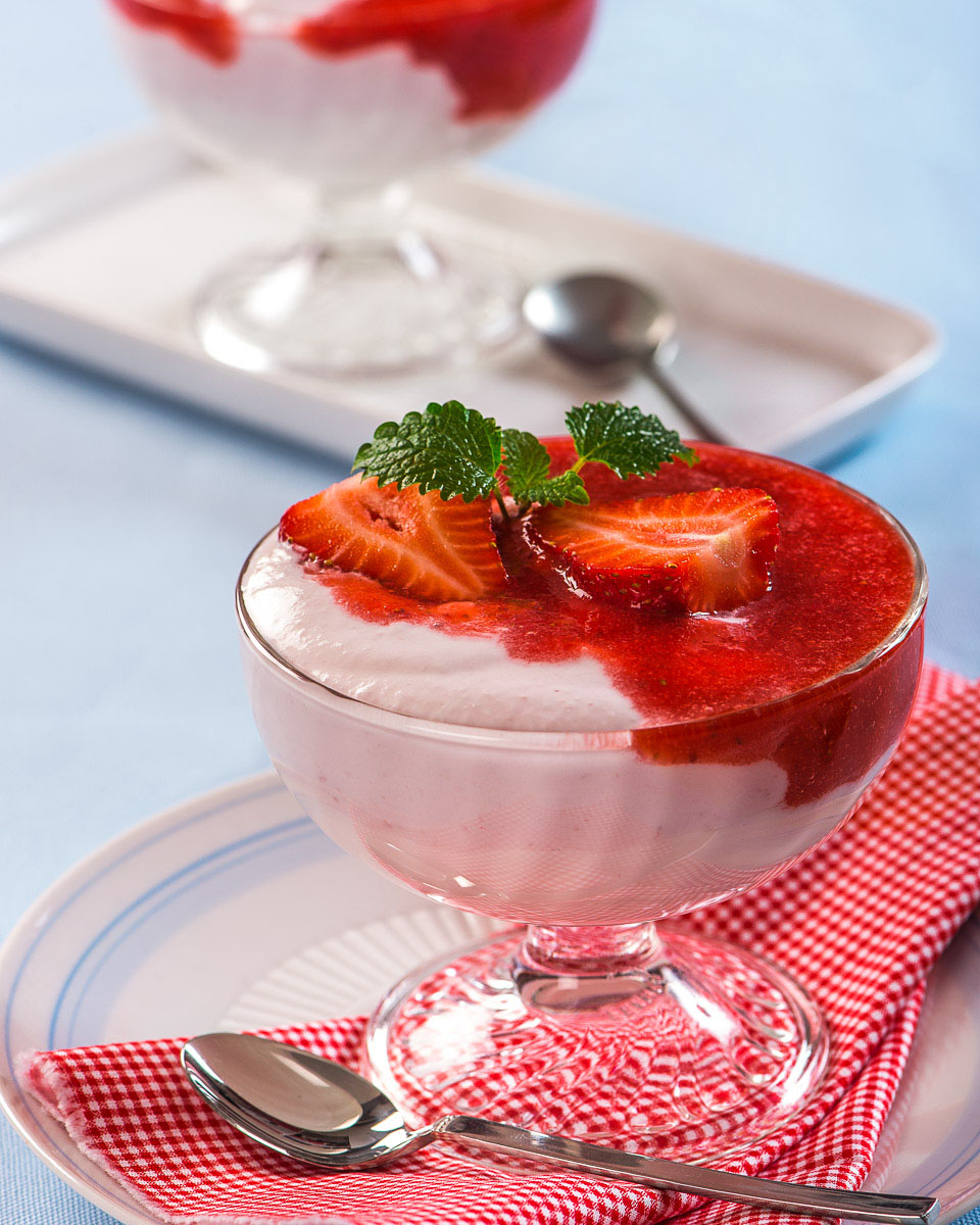 Ricotta-Erdbeer-Creme in Glas mit weißer Frischkäsecreme und Erdbeersoße, garniert mit frischer Erdbeere und Minzblättern, fotografiert von Alexandru Bialis in Österreich. Helle, frische Stimmung, inspirierend und appetitlich.
