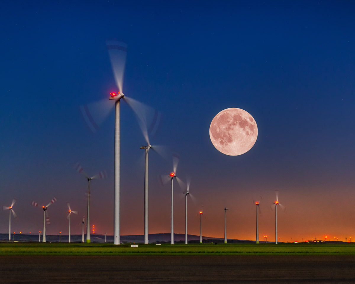 Supermond über dem Windpark Parndorf – Gewinnerfoto von Alexandru Bialis, aufgenommen im Burgenland, Österreich. Spektakuläre Aufnahme der rosa Mondnacht über Windrädern, Symbol für Natur, Energie und Ästhetik